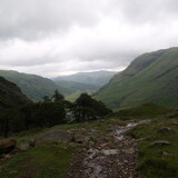 Pohled zpět k malému lesíku s vodopádem Taylorgill Force a dále do údolí s farmou Seathwaite